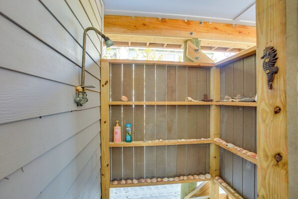 Una estantería de madera con un grifo metálico, repisas decoradas con caracolas y un caballito de mar decorativo.