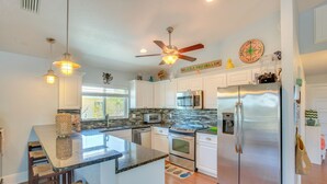 A modern kitchen with a central island, stainless steel appliances, and a ceiling fan. - Little Gasparilla Island Escape on Private Island! (Placida)