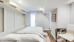 Un dormitorio con cama, una silla y una puerta que da a otra habitación.