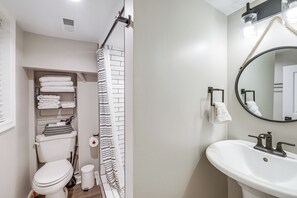 Un bagno con il water, lavandino e tenda per la doccia.