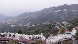 Un paisaje montañoso con edificios dispersos y una estructura blanca destacada con techo rojo en primer plano.