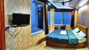 Un dormitorio con una cama, un televisor montado en la pared y una ventana con vistas al exterior.