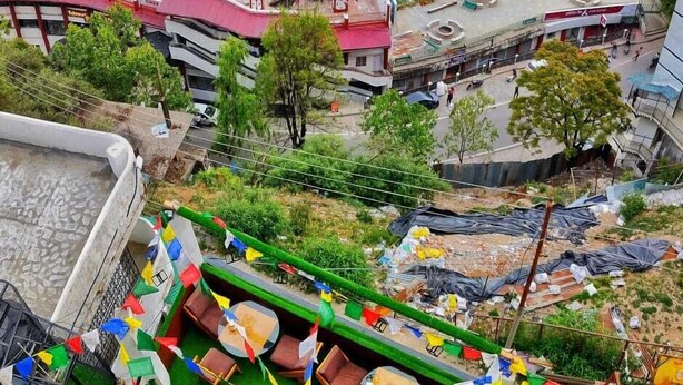 Terraza en la azotea con vistas a un paisaje montañoso, que incluye un área de comedor con mesas y sillas, y una piscina pequeña.
