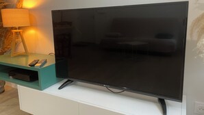 Ein Flachbildfernseher auf einer weißen Unterhaltungseinheit mit Fernbedienung und einer Lampe.