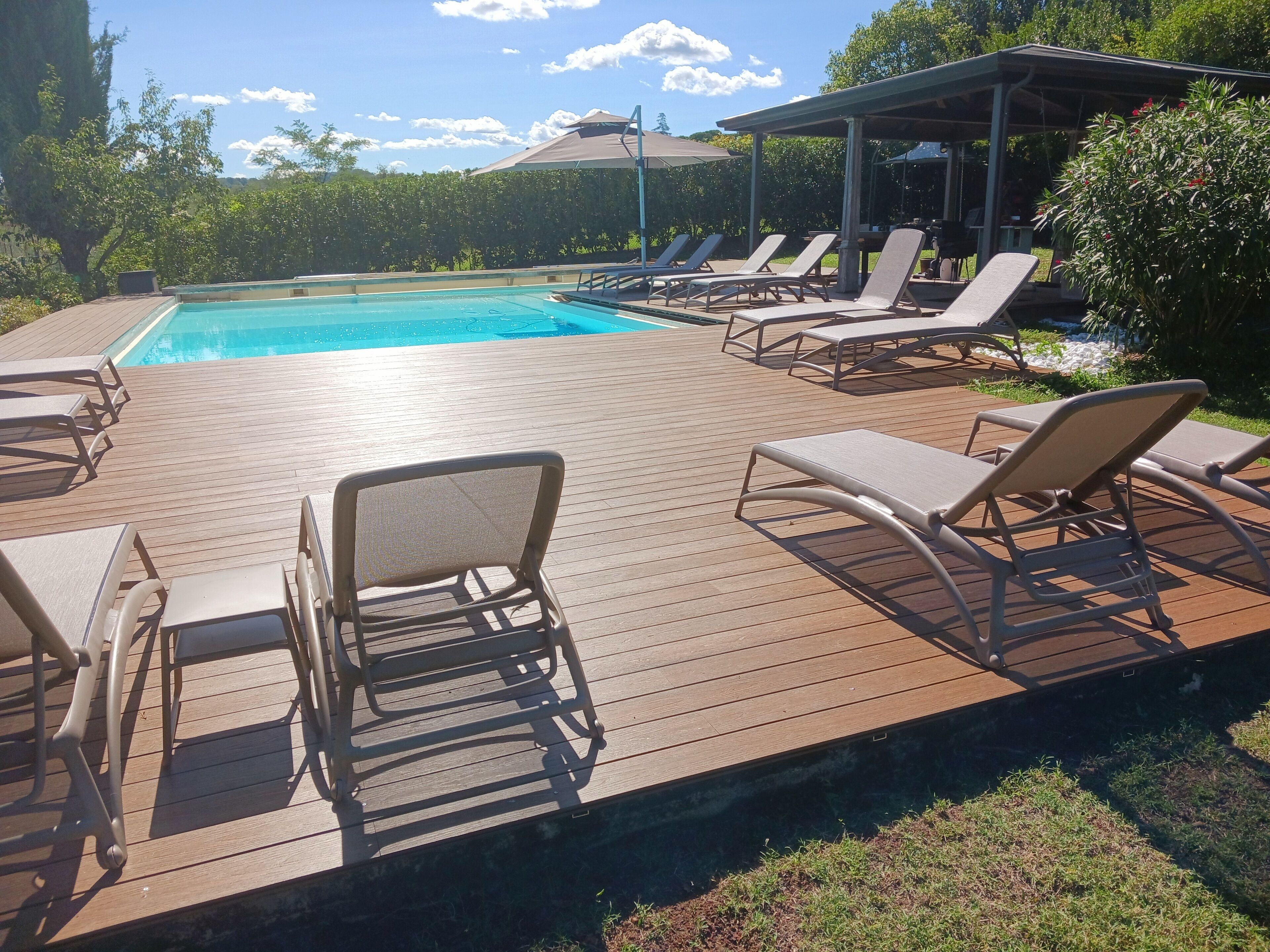 A wooden deck with lounge chairs and a pool.