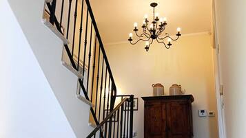 Una escalera con balaustres negros, un candelabro y un aparador con frascos.