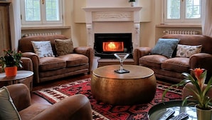 A living room with two brown leather sofas, a round coffee table, and a fireplace. - Tuscany Garden Inn (Castel San Pietro Terme)