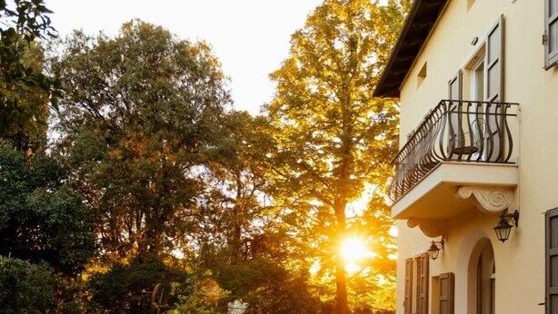A courtyard with stone flooring, outdoor seating, and a building with a balcony. - Tuscany Garden Inn (Castel San Pietro Terme)