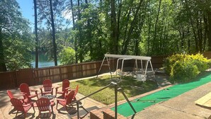 Eine Terrasse mit roten Stühlen und einer Schaukel, umgeben von einem Holzzaun und Bäumen.