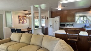 Eine moderne Küche mit Kühlschrank, Mikrowelle und Toaster, ein Essbereich mit Tisch und Stühlen sowie ein Wohnzimmer mit Sofa.