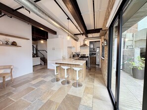 Une cuisine moderne dotée d’un îlot central, de tabourets de bar et offrant une vue sur l’extérieur.