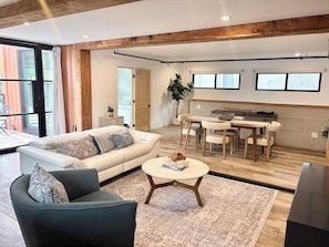 Un salon moderne comprenant un canapé, une table basse et un coin repas avec des chaises et une table.