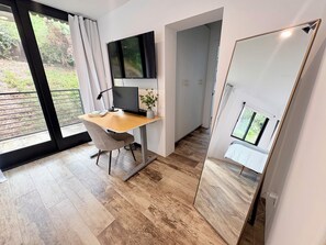 Un espace de bureau moderne comprenant un bureau, une chaise, un ordinateur et un grand miroir.