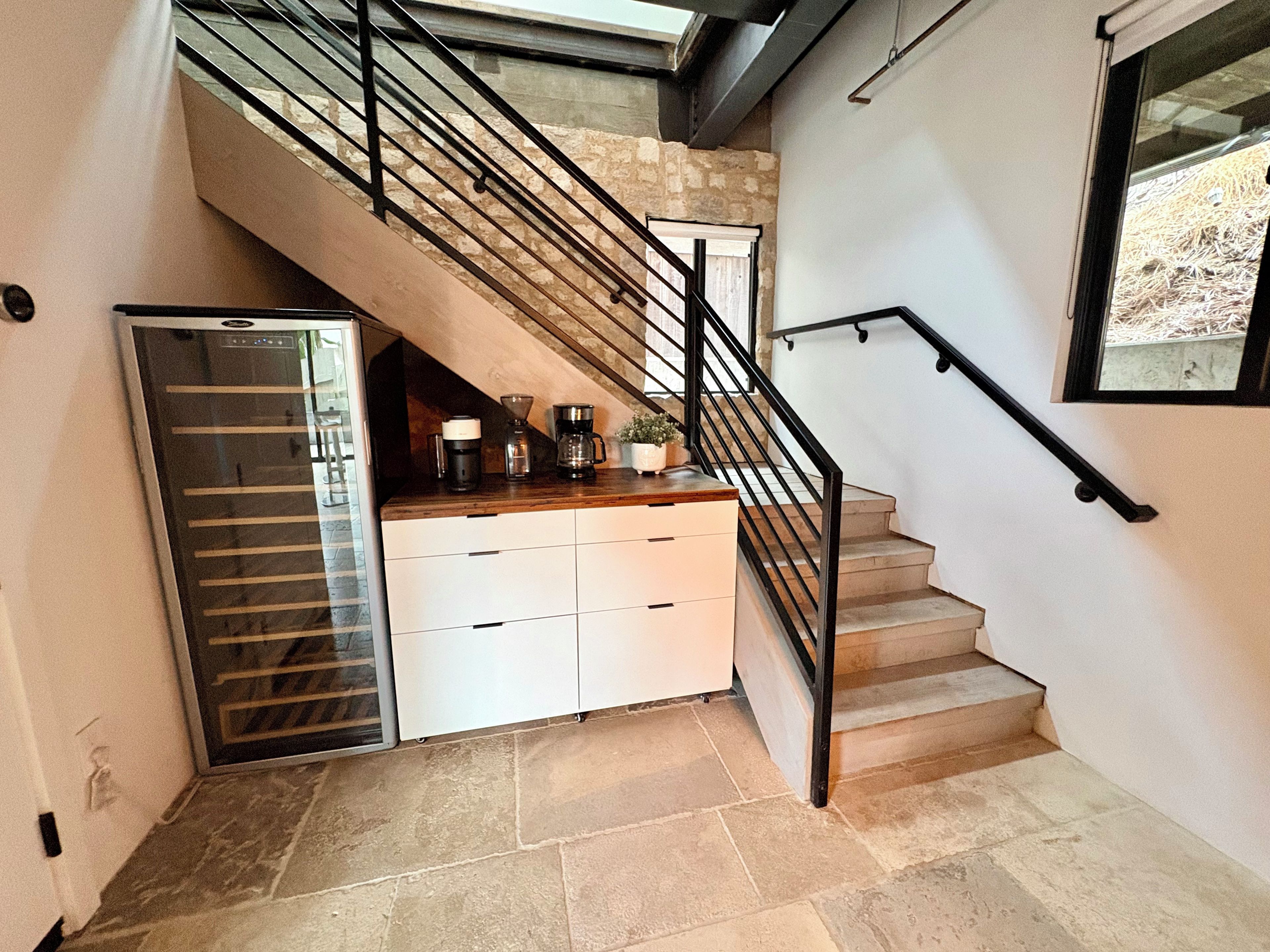 A modern kitchen with a built-in refrigerator, a coffee maker, and a potted plant on the counter.