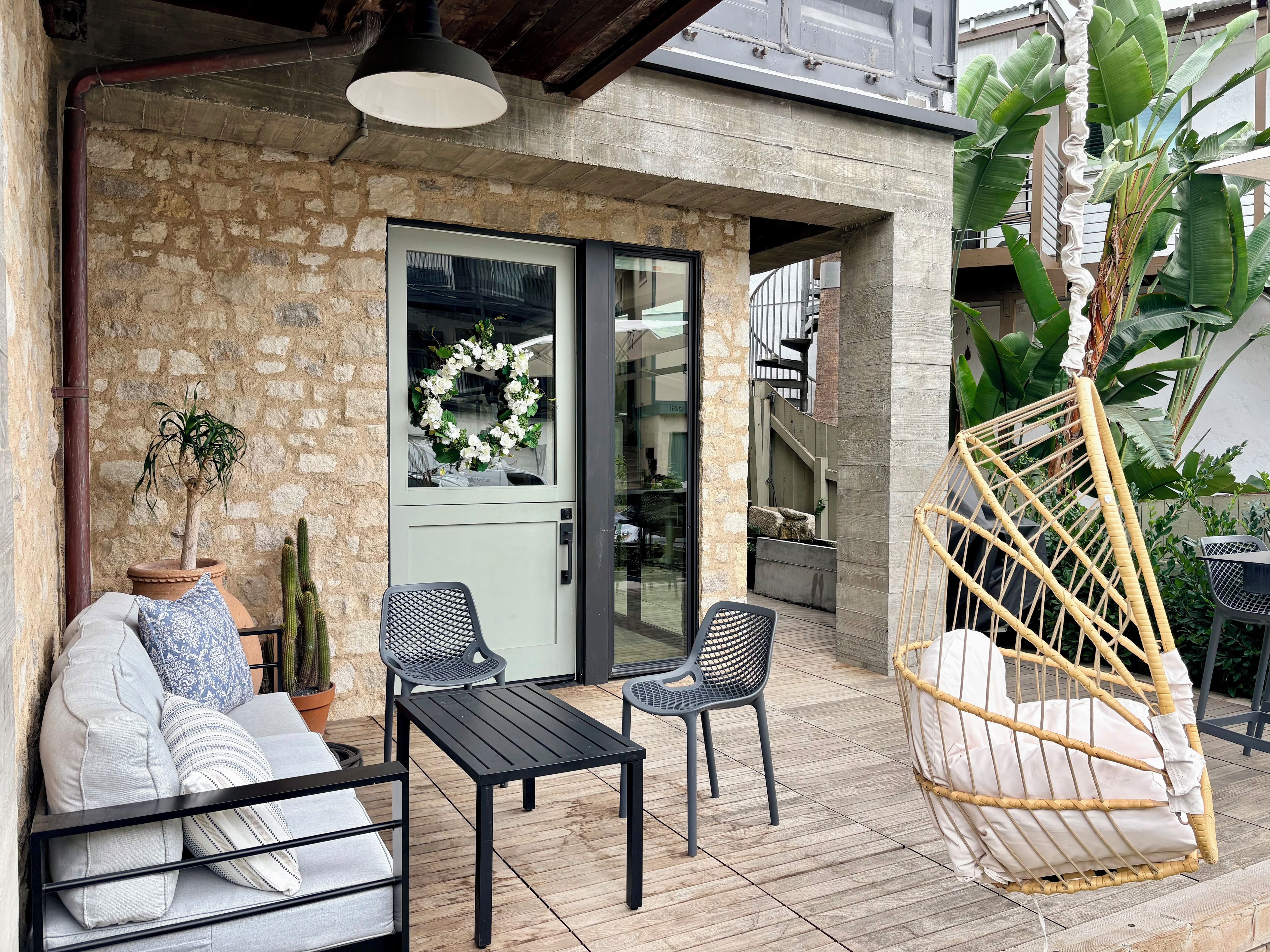 Un espace extérieur aménagé avec un canapé, deux fauteuils, une table et un fauteuil suspendu.