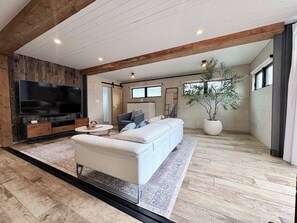 Un salon moderne avec un grand téléviseur à écran plat, un canapé, une table basse et une plante en pot.