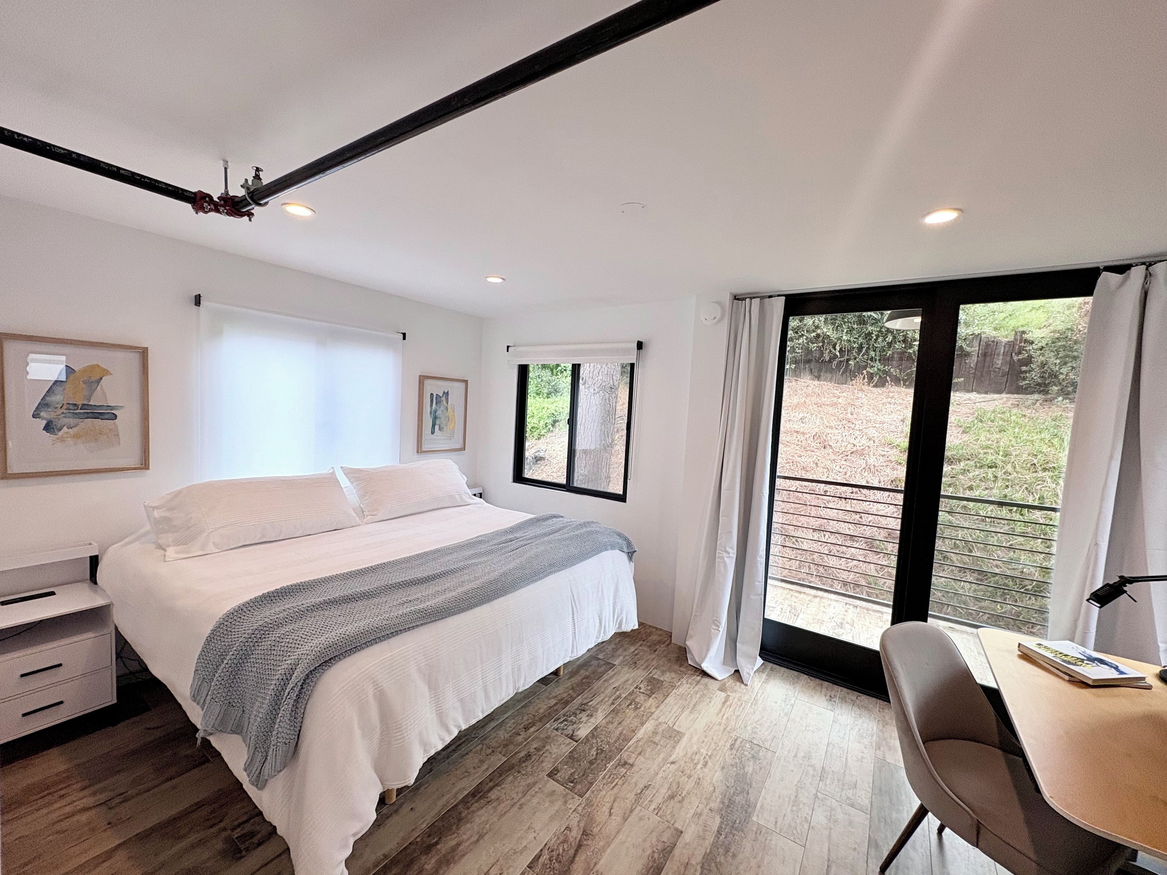 Une chambre à coucher avec un lit, un bureau et une fenêtre donnant sur l’extérieur.