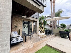 A patio with outdoor seating, a swing chair, and a covered area with a table and chairs. - Cali beach living! Modern 2 BR home. Pet friendly. Walk to town, beaches, harbor (Dana Point)