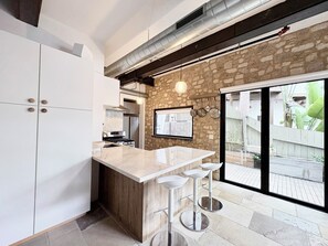 A modern kitchen with a stone wall, a large window, and a bar area with stools. - Cali beach living! Modern 2 BR home. Pet friendly. Walk to town, beaches, harbor (Dana Point)