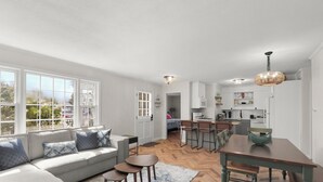 A modern living room with a sofa, two side tables, and a dining area with a table and chairs. - [New Listing] Walk To Beach, Main St, Harbor. Beautifully Renovated - Captain Gosnold Village (Hyannis)