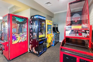 Een rij speelautomaten, waaronder Guitar Hero, Build-a-Bear en Hoop Fever.