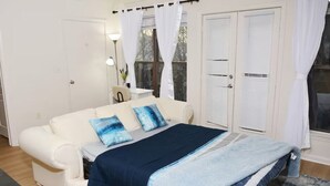 Un dormitorio con una cama, un sofá blanco y una ventana con cortinas.