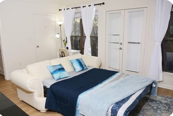 Un dormitorio con una cama, un sofá blanco y una ventana con cortinas.