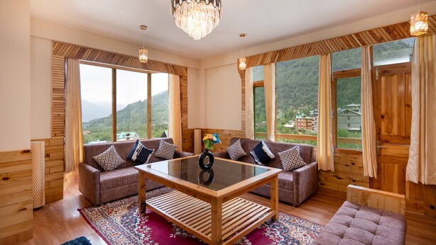 A spacious room with a large window, a wooden ceiling, and a chandelier. - Chirag Haveli Retreat (Manali)
