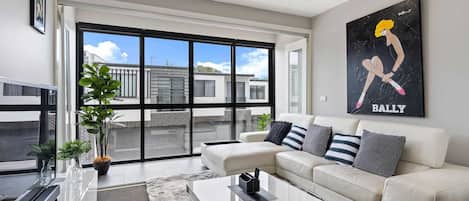 Una sala de estar moderna con un sofá, una mesa de centro y un ventanal con vistas a edificios.
