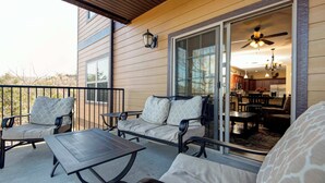 A covered patio with outdoor furniture, a sliding glass door to a kitchen, and a ceiling fan. - 51-06 Eagles Ridge Retreat, Spacious walk-in.  Balcony, mountain views, indoor/outdoor pools/splash pads.  Close to SDC. (Branson)