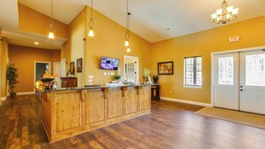 A reception area with a wooden counter, a television, and a chandelier. - 51-06 Eagles Ridge Retreat, Spacious walk-in.  Balcony, mountain views, indoor/outdoor pools/splash pads.  Close to SDC. (Branson)
