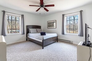 A bedroom with a bed, a ceiling fan, and large windows.