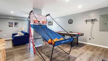 A living room with a blue couch, a coffee table, and a pool table.