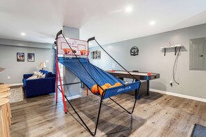 A living room with a blue couch, a coffee table, and a pool table.