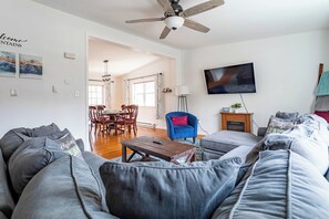 A modern living room with a gray sofa, a blue armchair, a wooden coffee table, and a TV mounted on the wall. - My Blue Heaven | Game Area | 4 BDR | Pet Friendly (Albrightsville)
