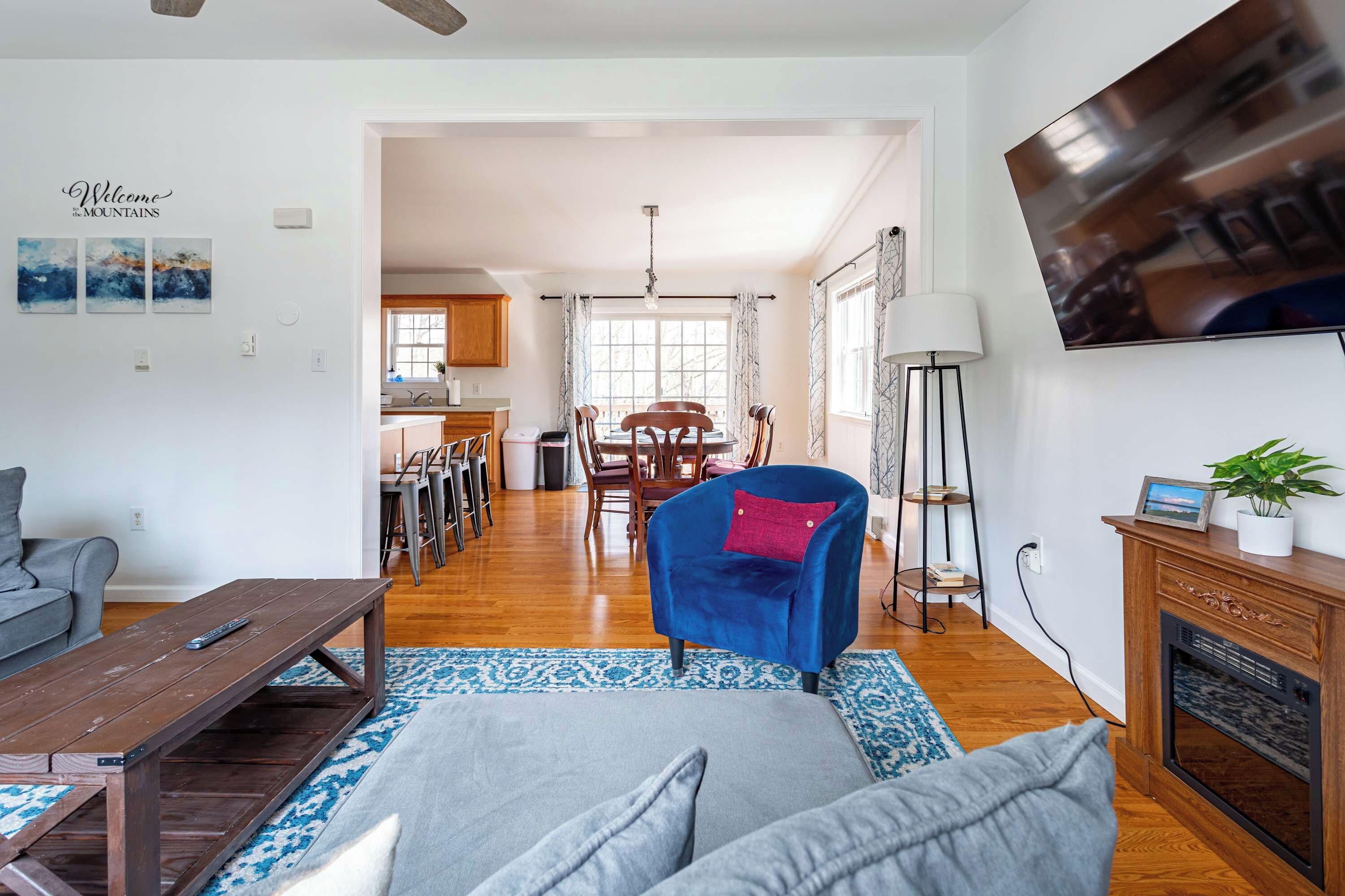 A living room with a sofa, a coffee table, a blue chair, a TV, and a fireplace.