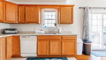 Una cocina con armarios de madera, lavavajillas, tostadora y ventana con vistas.