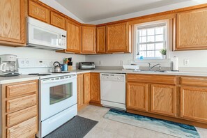 A modern kitchen with wooden cabinets, a microwave, stove, dishwasher, and a window with a plant. - My Blue Heaven | Game Area | 4 BDR | Pet Friendly (Albrightsville)