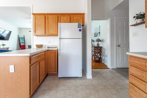 A kitchen with wooden cabinets, a white refrigerator, and a tiled floor. - My Blue Heaven | Game Area | 4 BDR | Pet Friendly (Albrightsville)