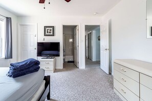 A bedroom with a bed, a TV, a dresser, and a door leading to another room. - My Blue Heaven | Game Area | 4 BDR | Pet Friendly (Albrightsville)