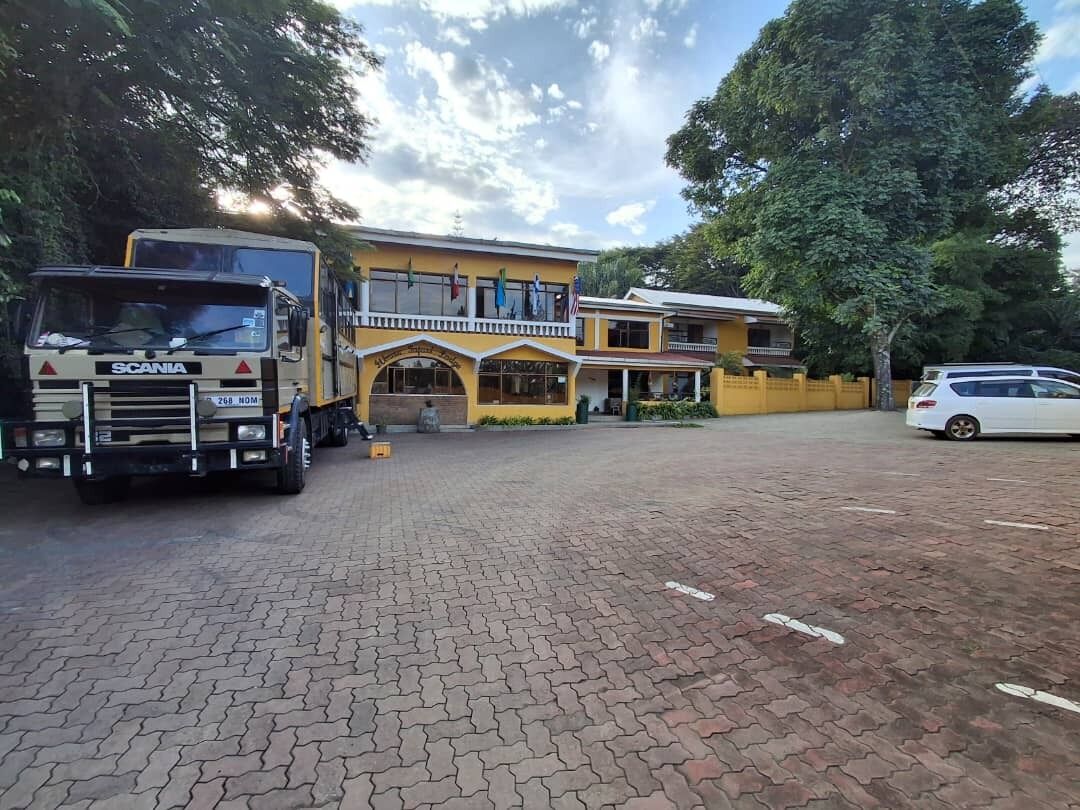 A building with a yellow facade, a covered entrance, and a paved driveway.