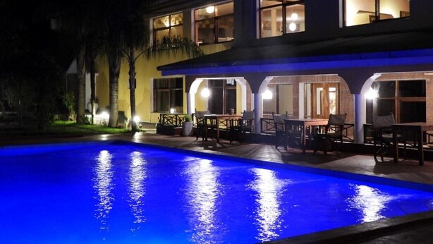 Un bâtiment à deux étages avec une piscine à l’avant, doté d’un espace extérieur aménagé pour s’asseoir et d’un balcon.