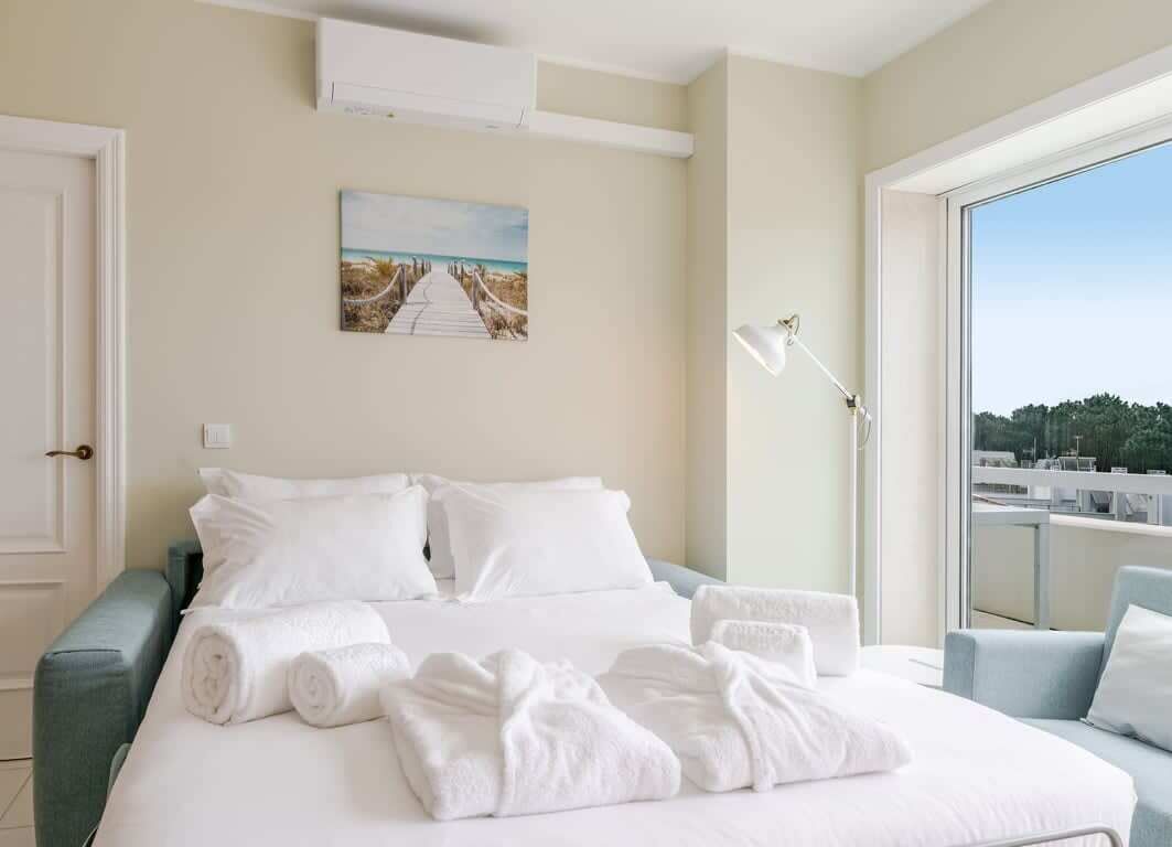 Ein Hotelzimmer mit einem Bett, Handtüchern, einem Gemälde, einer Lampe und Blick durch ein großes Fenster.