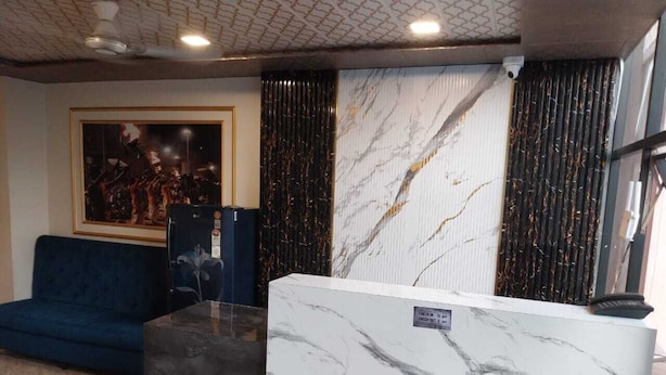 A reception area with a marble counter, a blue sofa, and a framed picture on the wall. - Kashi Kutir (Varanasi)