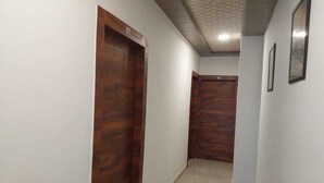 A narrow hallway with wooden doors and a carpeted floor. - Kashi Kutir (Varanasi)