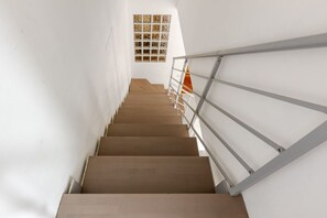 A staircase with wooden steps and metal railings, leading to a landing with a patterned wall.