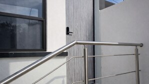 A modern exterior with a metal handrail, a door, and a window.