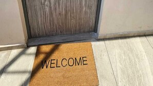 A wooden door with a metal handle and a welcome mat at the entrance.