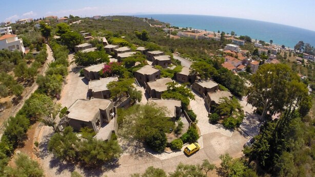 A coastal residential area with compact houses, a paved road, and a yellow car. - Cavo Grosso Bungallows (Mavrovouni)