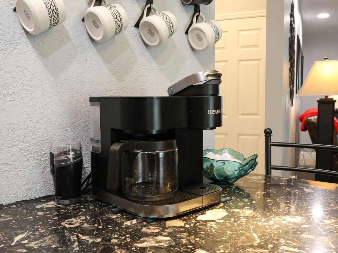 En kaffemaskine på en køkkenbordplade med en krystal kande og en kop.